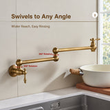 A brass wall-mounted pot filler faucet with dual articulated joints extending over a sink beside a bowl.