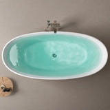 An overhead view of a modern oval bathtub with teal water set against a neutral wall.