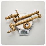 Two antique-style brass plumbing valves and a matching flange ring displayed on a digital scale against a plain background