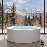 A modern round bathtub in a scenic mountain setting with trees and snow-capped peaks in the background.