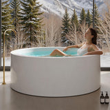 A woman relaxing in a modern round massage bathtub in a snowy landscape.