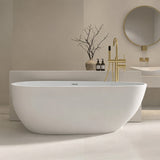 A modern oval white bathtub with a gold faucet in a minimalist bathroom setting