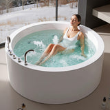 A woman relaxing in a modern round bathtub filled with water, set near a large window overlooking a snowy landscape.