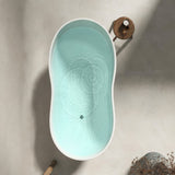 An overhead view of a modern, oval-shaped bathtub with gentle water ripples.