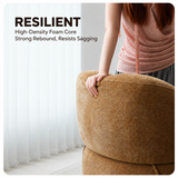 Close-up of a hand pressing the rounded backrest of a light brown chenille swivel barrel chair against sheer white curtains