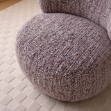 Close-up of a mottled lilac-gray swivel barrel chair seat cushion on a cream textured rug