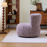 Mottled lilac loop yarn swivel barrel chair on a pale rug in a wood-accented living room with floor lamp and shelf