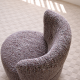High-angle view of a mottled lilac-gray loop yarn swivel barrel chair on a cream rug