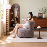 Woman reading in a mottled brown loop-yarn swivel barrel chair in a warm living room