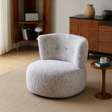 Light gray textured swivel barrel chair on a woven rug beside a wood side table and cabinet in a warm living room