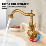 Vintage brass kitchen faucet with a curved spout and side lever, shown on a beige marble countertop with running water.