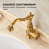 Vintage brass kitchen faucet with floral engravings, curved spout, and side lever, set against a beige marble countertop.