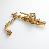 Brass vintage faucet with floral carvings and rosette lever, lying on white background.