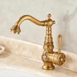 Brass vintage kitchen faucet with floral engravings, curved spout, and side lever, displayed on a beige marble countertop.