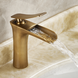 Vintage copper kitchen faucet with waterfall water output, sleek design and curved handle, set against a beige countertop.