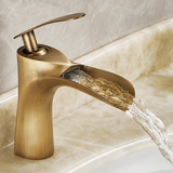 Copper kitchen faucet with a waterfall spout, showcasing a sleek design and flowing water, installed on a countertop.