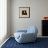 Light blue barrel chair on a blue checkered rug in a bright room with abstract art