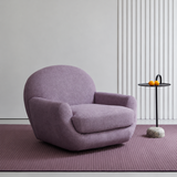 Lilac swivel barrel chair in a room with fluted wall, plum rug, and black side table