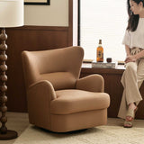 Tan upholstered swivel barrel chair in a wood-panelled room, with a woman seated on the windowsill beside it.