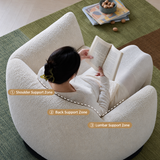 Woman reading in a white textured swivel barrel chair on a green rug, with labeled shoulder, back and lumbar support zones