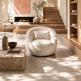 Cream bouclé swivel chair with pillow, stacked wooden steps and lit fireplace behind