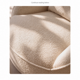 Close-up of cream bouclé swivel barrel chair seat, piped front edge and dense looped texture in sunlight
