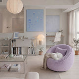 Lilac bouclé swivel barrel chair with pillow, throw and a white cat, in a bright living room with framed blue artwork