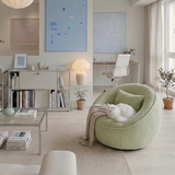 Pale green textured swivel barrel chair with a white cat in a bright home office living room