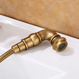 Brushed antique brass pull-out faucet spray head in close-up on a white countertop.