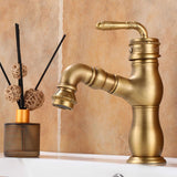 Brushed antique brass kitchen faucet with carved lever handle by a beige tiled wall