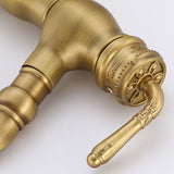 Close-up of a carved vintage brass kitchen faucet handle and spout base on a white background