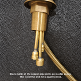 Close-up of brass faucet's threaded base, copper pipe joints and braided hose.
