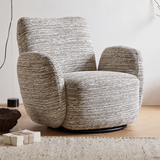 Two-tone grey textured swivel barrel chair on a black base in a bright room with a rug, wrapped box and dark bowl