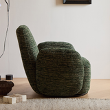 Rear view of green textured swivel barrel chair showing curved wraparound back in a bright room with light wood floor