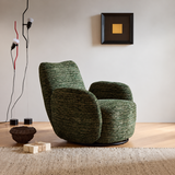 Green textured swivel barrel chair angled on wood floor with bowl, wrapped box and floor lamps