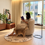 Oatmeal bouclé swivel barrel chair by a sunny window, reader and cat nearby