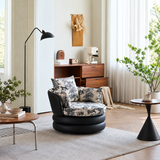 Black swivel barrel chair with toile horse-print cushions beside a coffee table and floor lamp in a bright living room