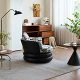 Black swivel barrel chair with toile cushions seen from behind in a warm wood-furnished room