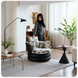 Woman adjusting the woodland toile cushion of a black swivel barrel chair in a styled living room