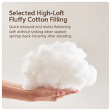 Hands holding a loose clump of white fluffy cotton filling against a beige studio background, filling close-up