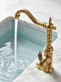 Brass kitchen faucet with wood-grain handle, water flowing into a light blue sink on a marble countertop.