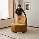 Tan swivel barrel chair with 360° Swivel label as a woman turns it in a warm room