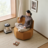 Tan pumpkin-shaped barrel chair with a seated woman reading in a sunlit room