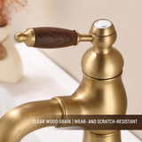 Close-up of a brushed brass kitchen faucet lever handle with wood-grain grip and red-blue indicator cap.