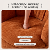 Bare foot pressing into a rust-orange chenille swivel barrel chair seat, showing cushion give and woven fabric texture.