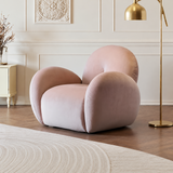 Blush pink velvet swivel barrel chair in a paneled room with gold floor lamp and herringbone wood floor