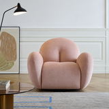 Blush pink swivel barrel chair with rounded back and black base in a white paneled room.